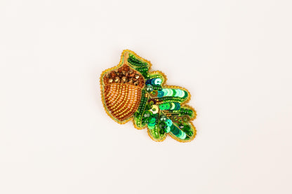 a green and gold brooch with a leaf design