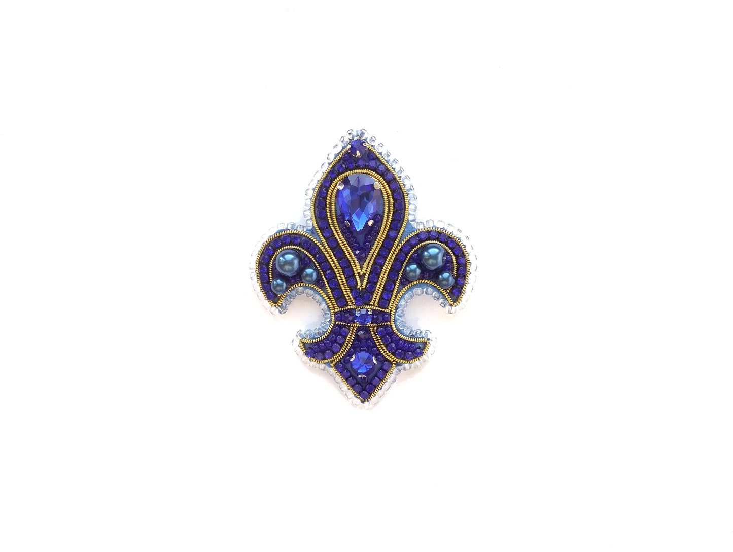 A decorative blue and gold brooch with a central gemstone surrounded by smaller gemstones and intricate designs.