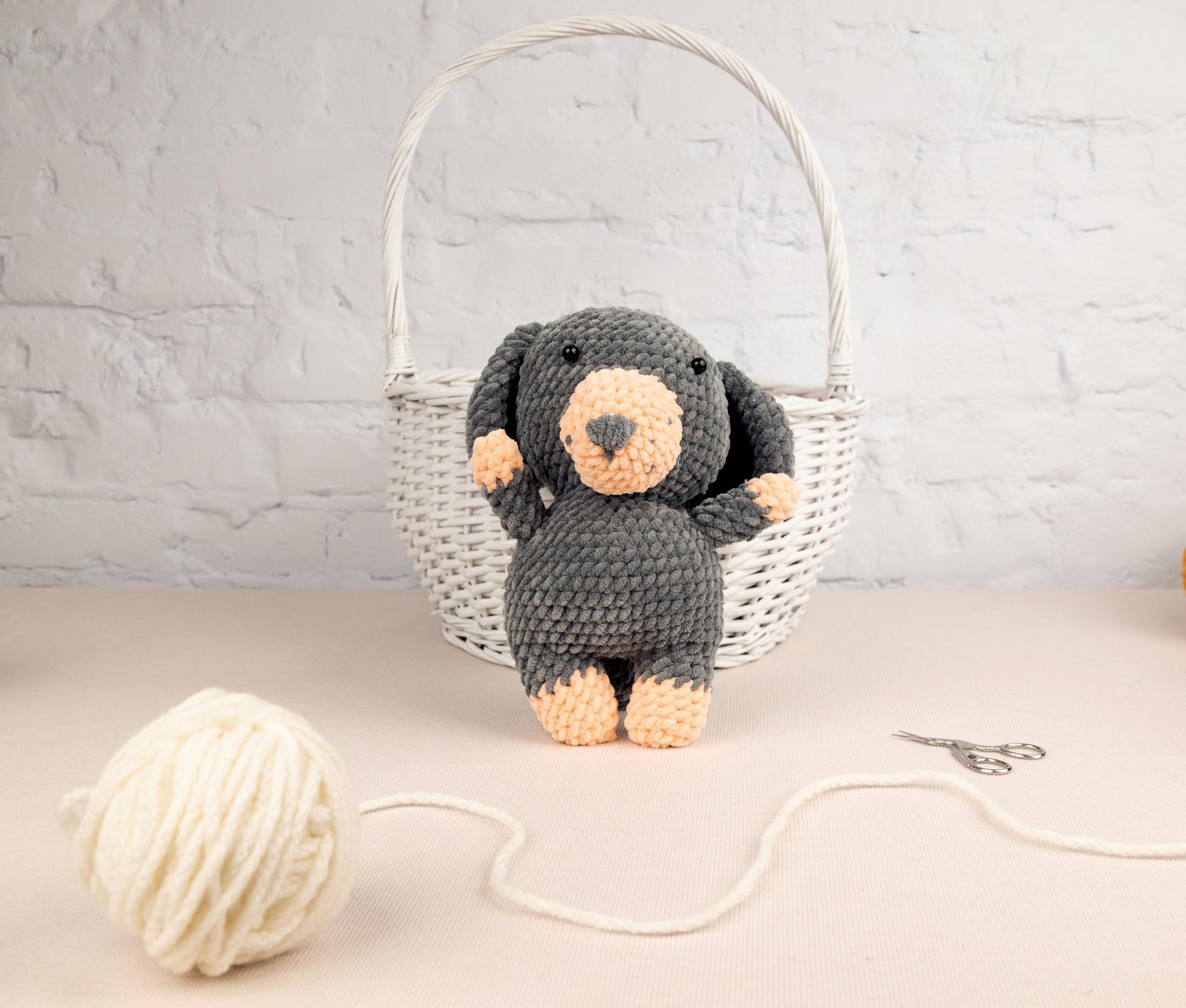 a crocheted teddy bear sitting next to a ball of yarn