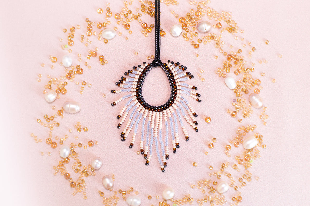 a beaded necklace with a large, open pendant surrounded by scattered pearls and beads in various shades of gold and white.