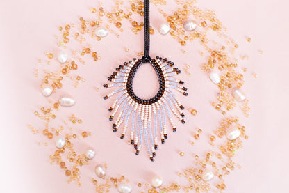 a beaded necklace with a large, open pendant surrounded by scattered pearls and beads in various shades of gold and white.