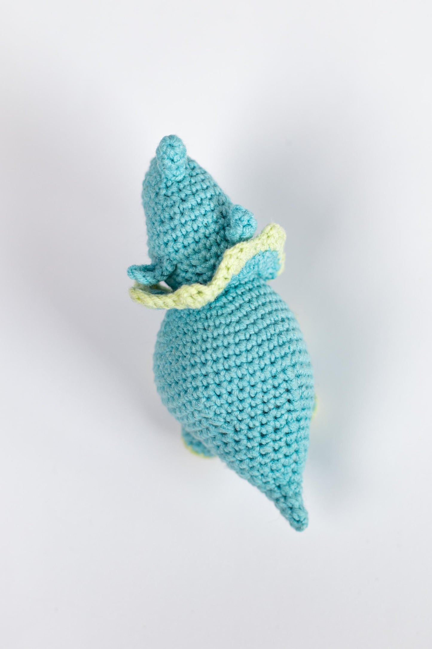 a crocheted blue stuffed animal with a yellow ribbon