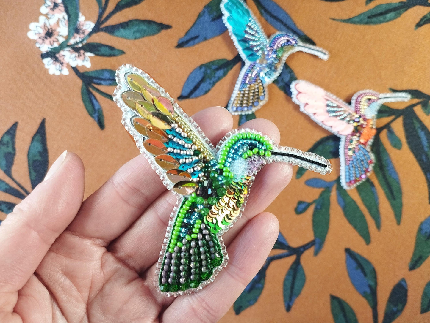 a person is holding a piece of beaded art