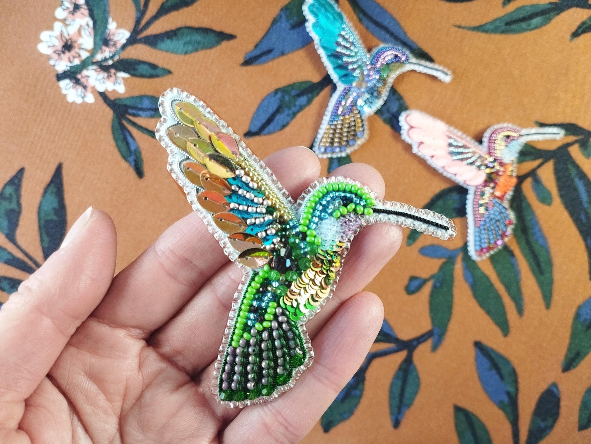 a person is holding a piece of beaded art