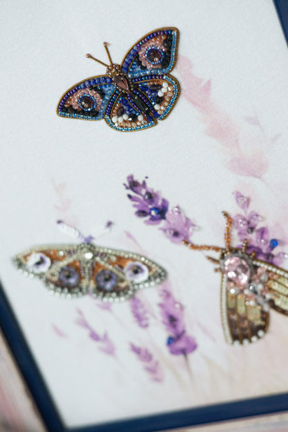 a close-up view of two intricately designed butterflies, one with a blue and purple color scheme and the other with a brown and gold color scheme. The butterflies are adorned with various embellishments, including jewels and flowers, adding to their detailed and visually appealing appearance.