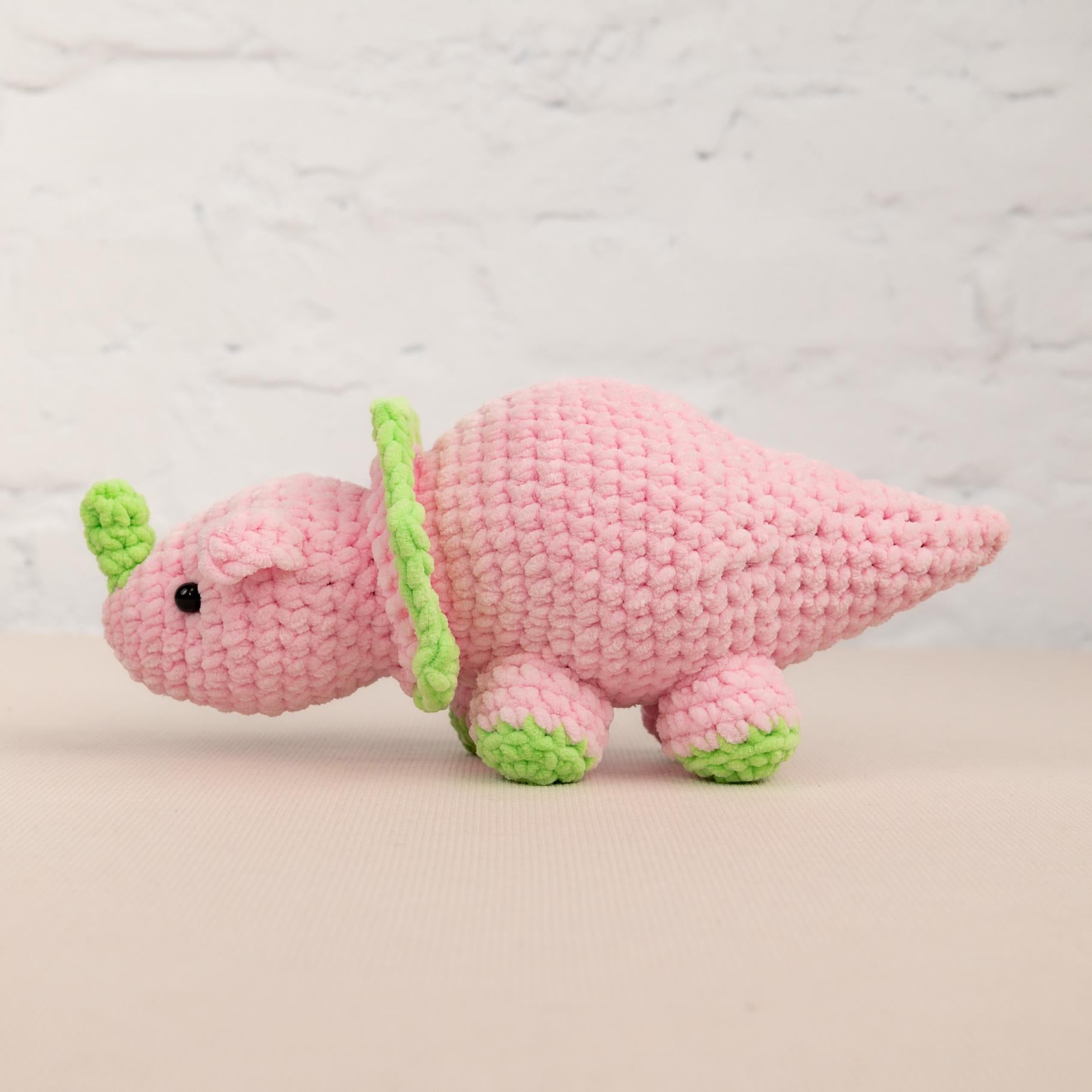 a pink crocheted toy with a green tail