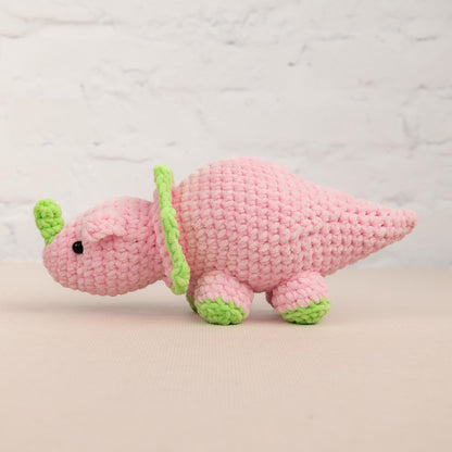 a pink crocheted toy with a green tail