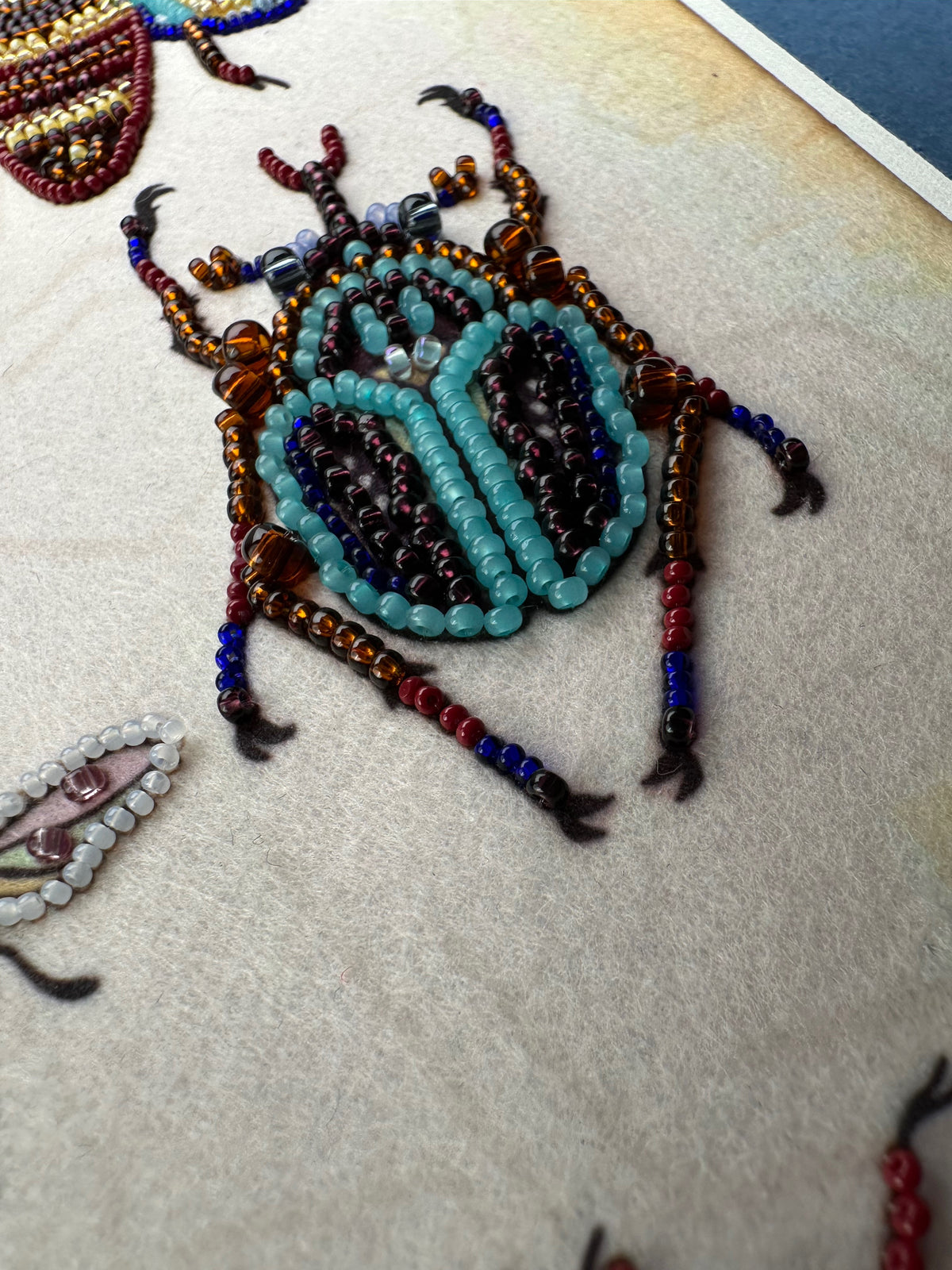 a close-up view of a detailed and colorful beaded insect, possibly a dragonfly or a beetle, crafted from various colored beads.