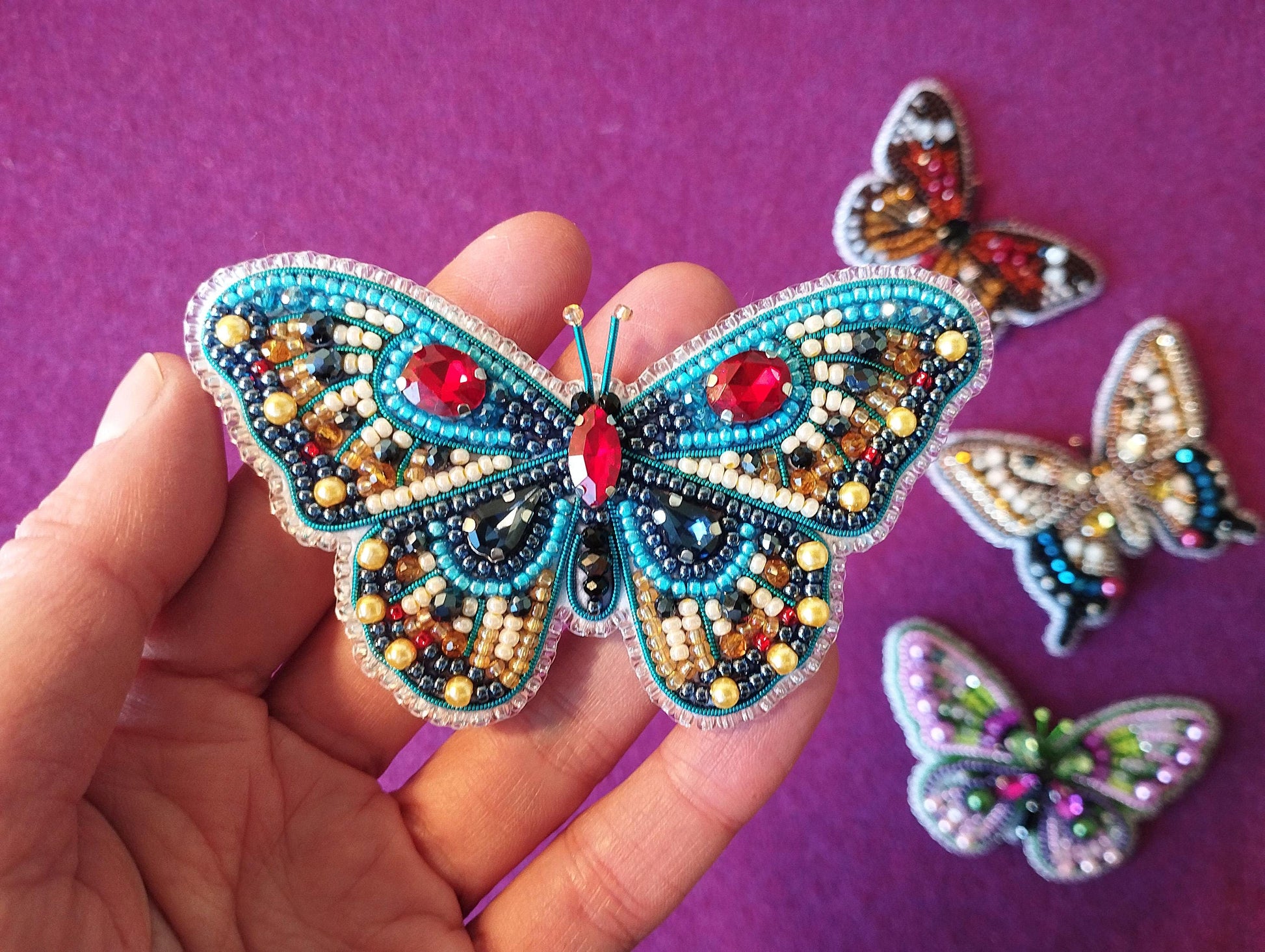 a hand is holding a small butterfly brooch