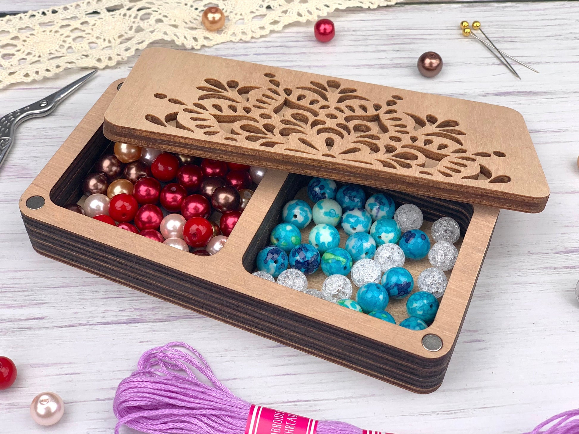 a wooden box filled with beads next to a pair of scissors