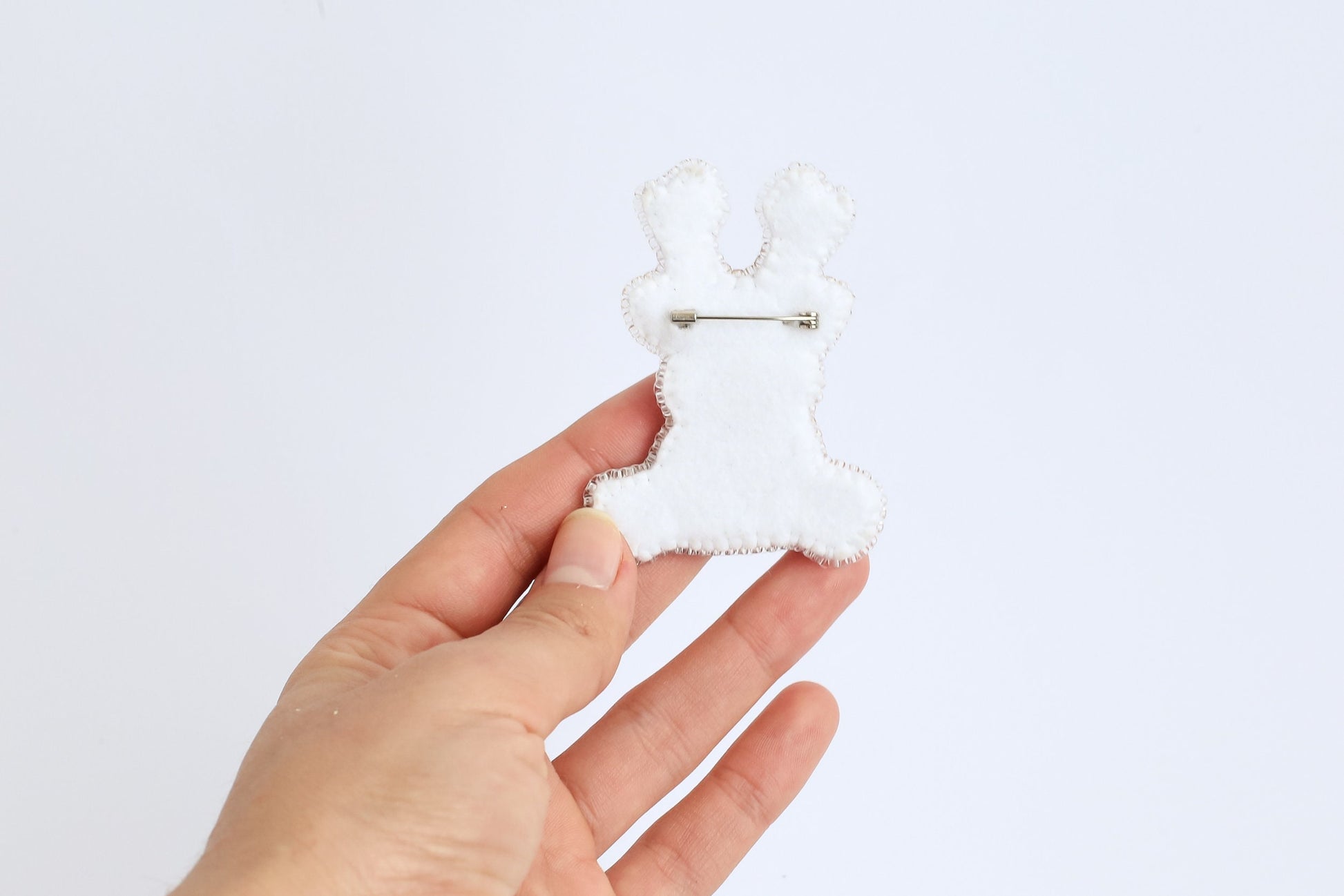 a person is holding a white brooch in their hand