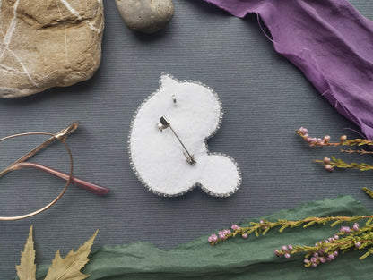 a variety of objects, including a pin cushion, glasses, a rock, a piece of fabric, and some flowers, arranged on a grey background.