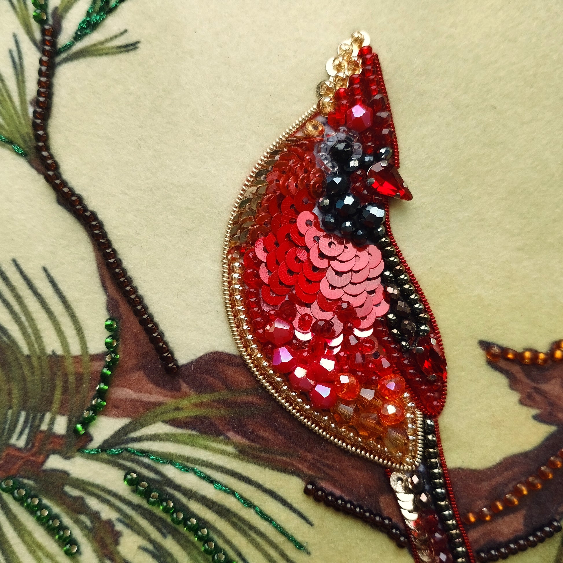 a close-up view of a vibrant, sequined bird perched on a branch. The bird is adorned with a variety of colorful sequins, giving it a striking and eye-catching appearance. The branch on which the bird is perched is intricately detailed, showcasing the craftsmanship involved in creating this piece of art.