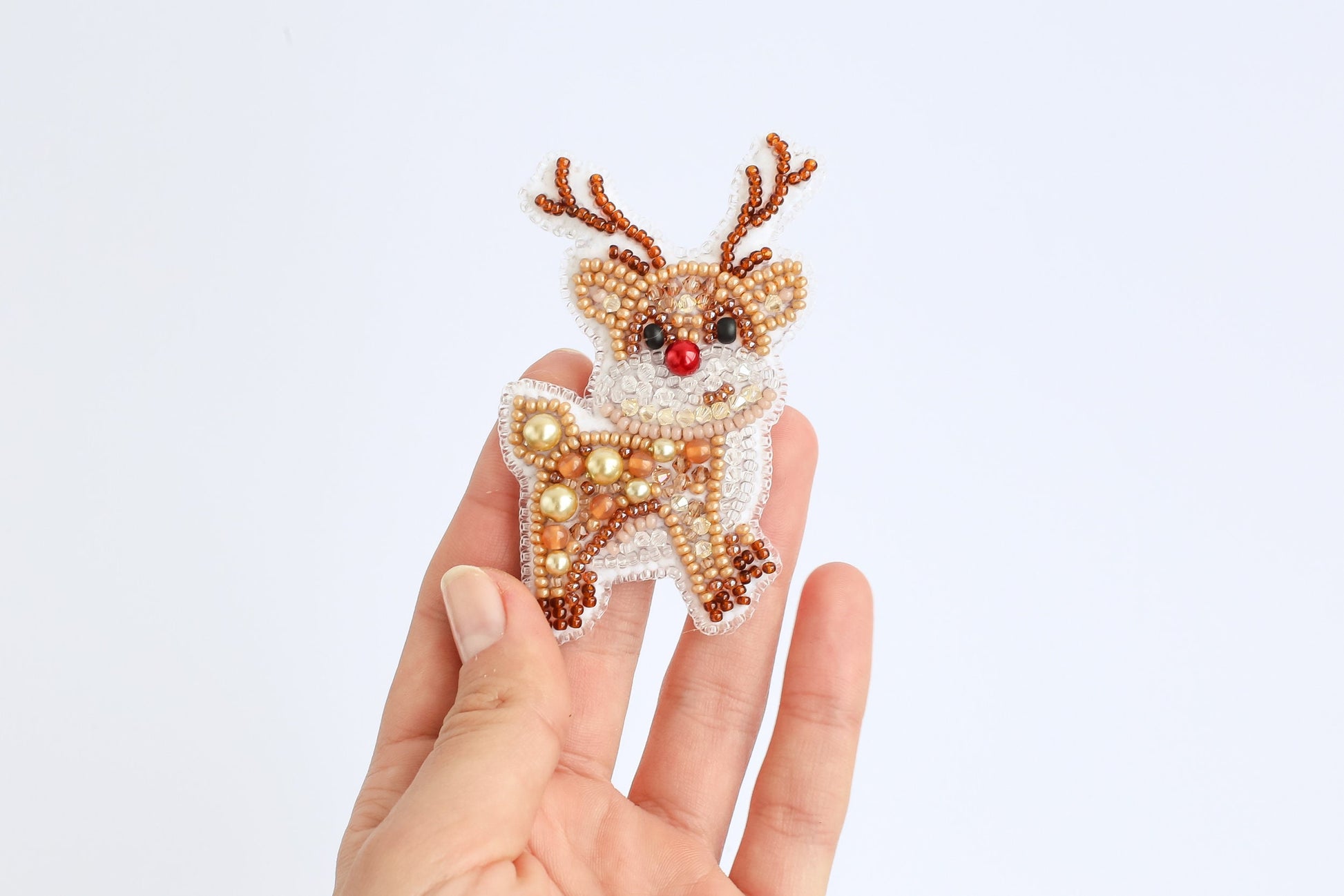 a hand holding a beaded christmas ornament