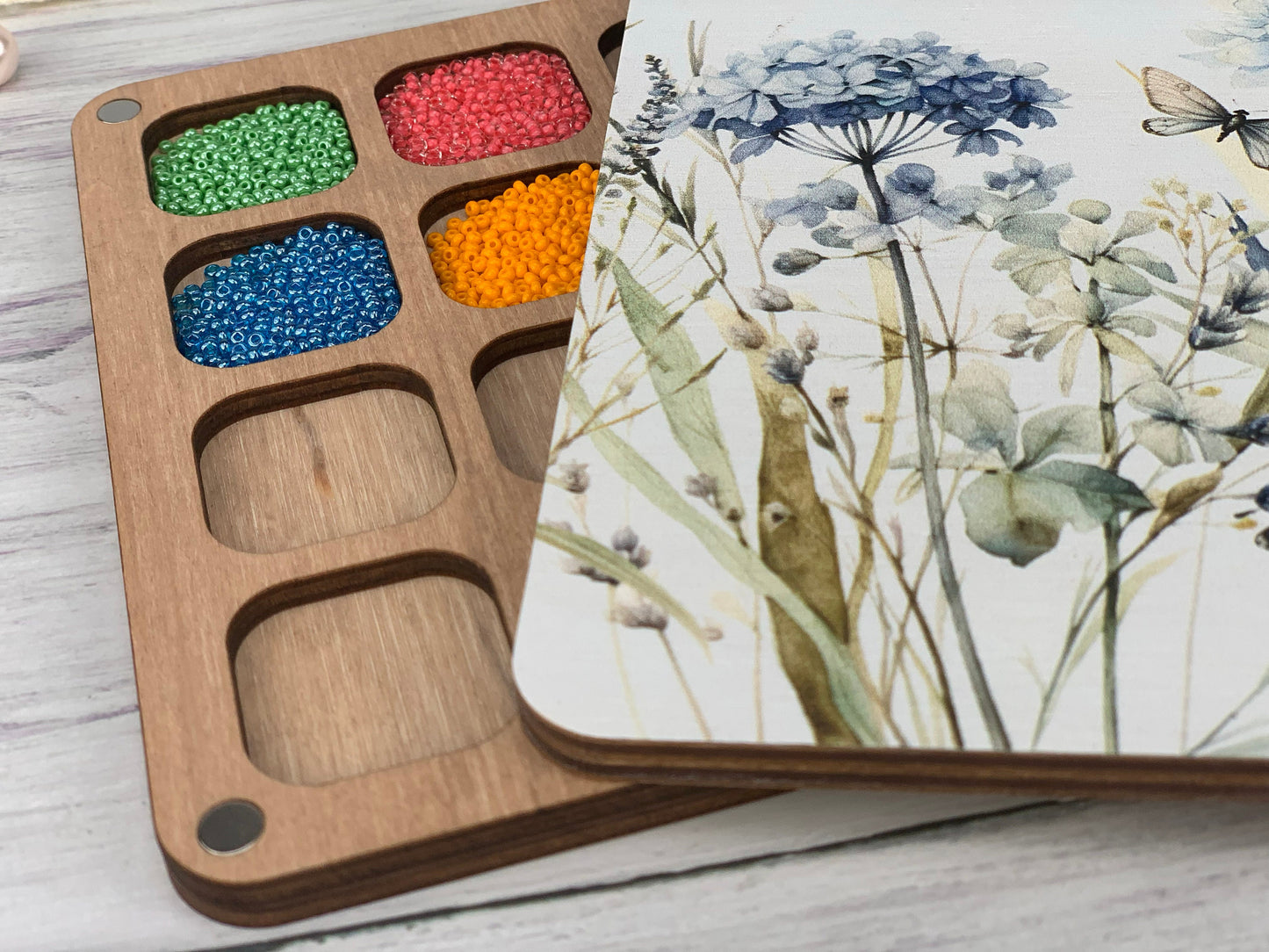 a box of seed beads sitting on top of a wooden tray