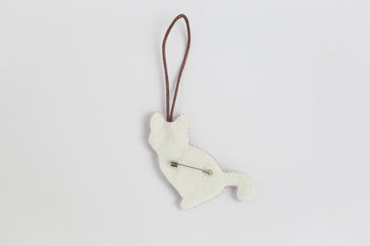 a white dog ornament hanging on a brown cord