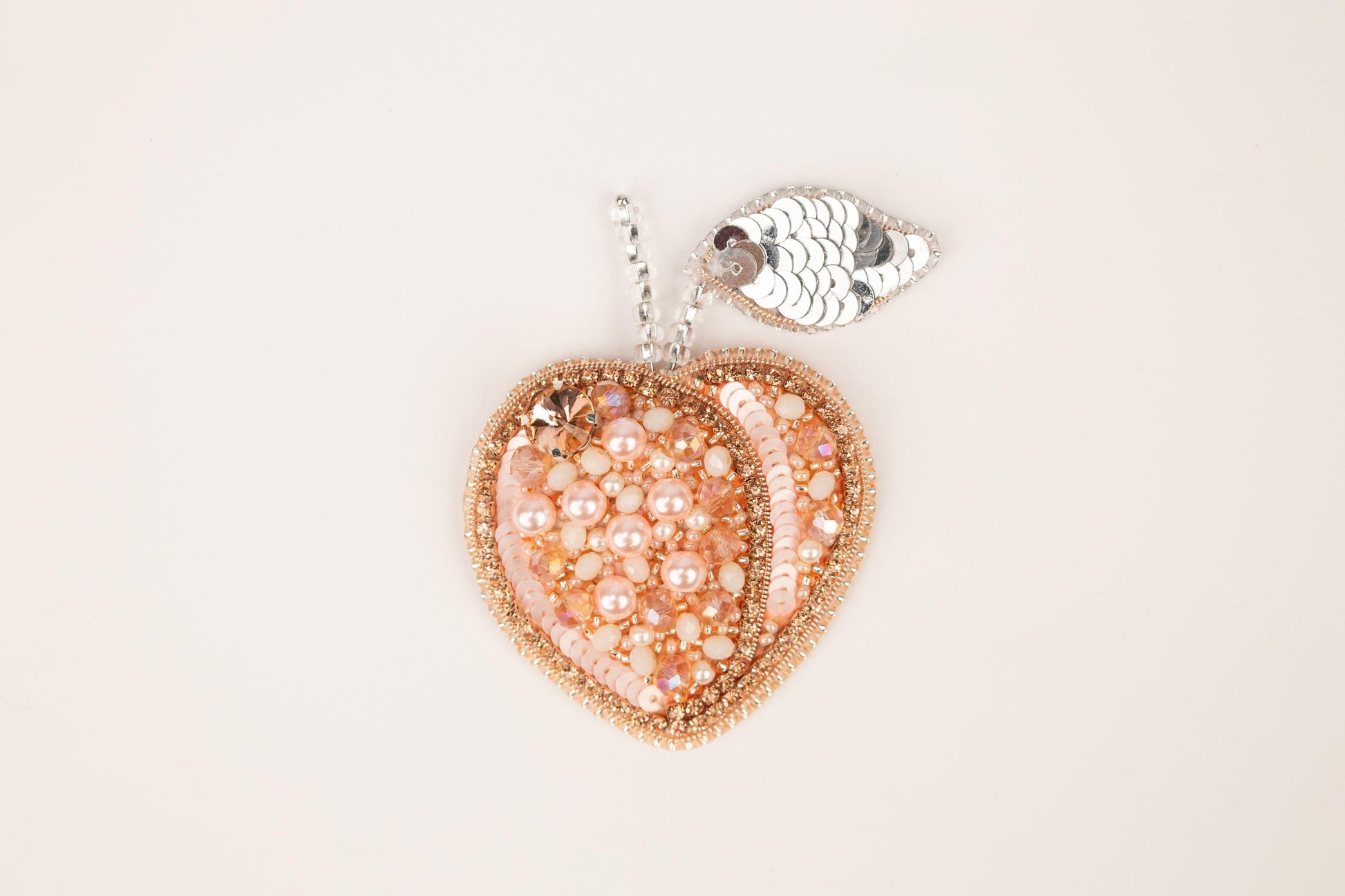 a heart shaped beaded pendant with a fish charm