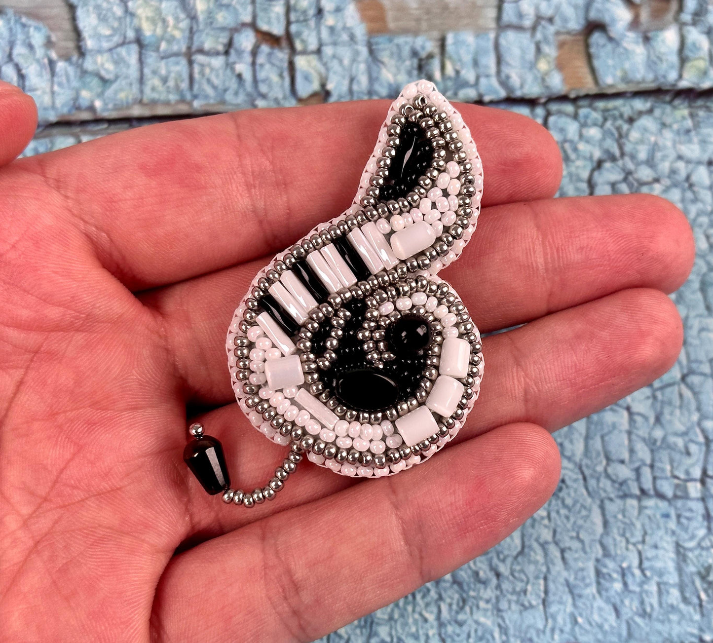 a person holding a beaded brooch in their hand