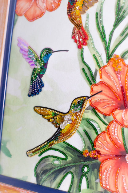 two colorful hummingbirds, one with a purple and green body and the other with a yellow and green body, surrounded by vibrant flowers and lush foliage.