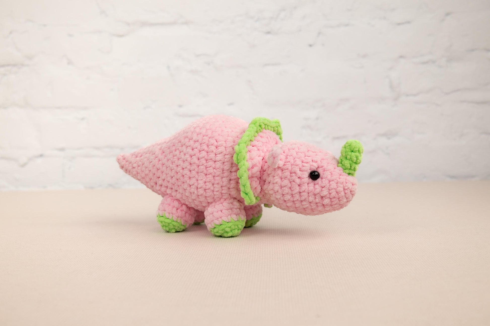 a crocheted pink elephant with a green tail