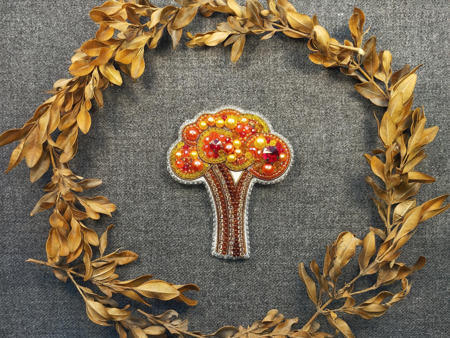 a brooch with a tree on it surrounded by leaves