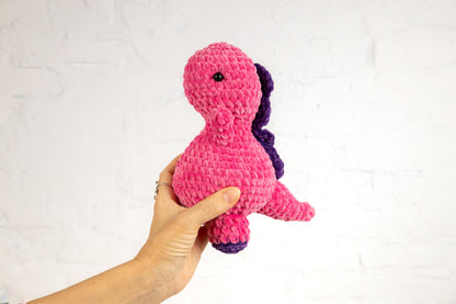 a hand holding a pink and purple stuffed animal
