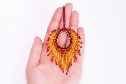 A hand holding a colorful beaded necklace with a large, eye-catching design.