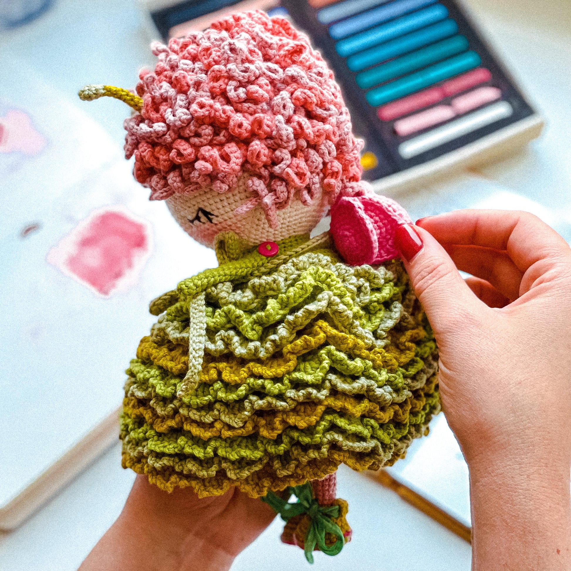 a crocheted doll sitting on top of a pile of yarn