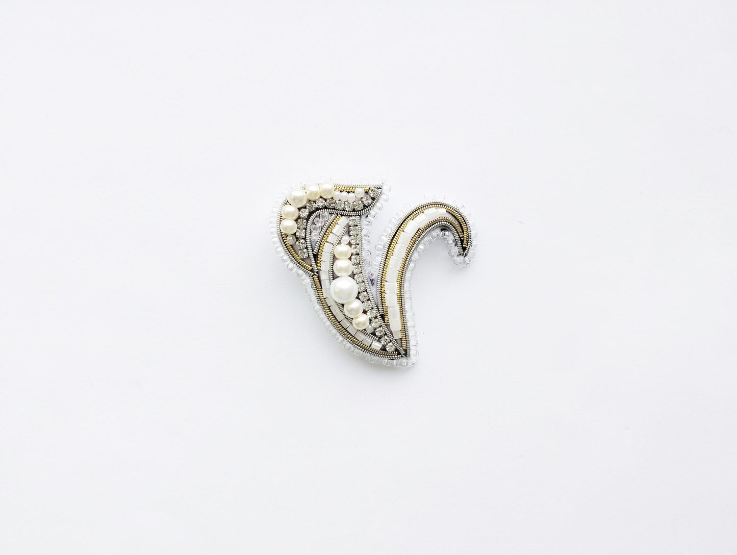 A decorative piece of jewelry, possibly a brooch or pendant, is shown against a plain white background.