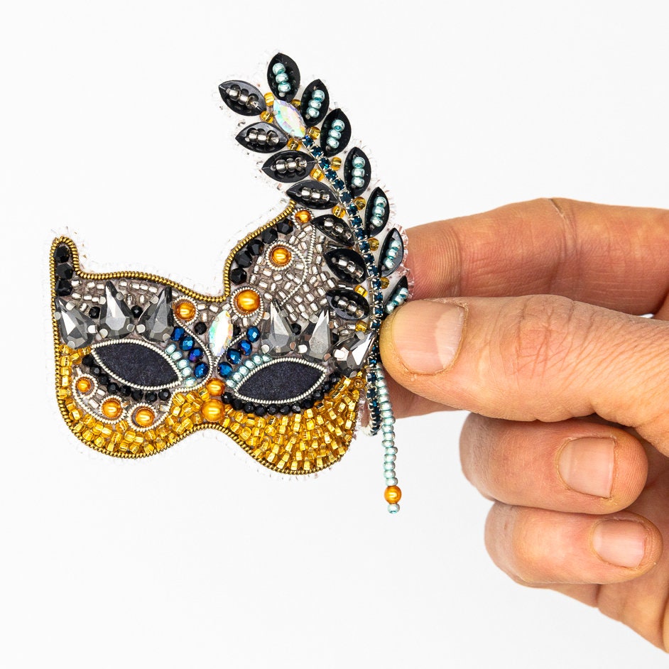 a hand holding a mask with beads and beads