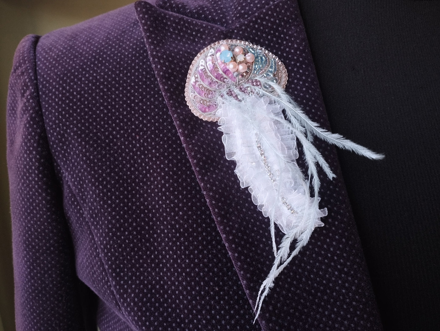 A close-up view of a purple jacket with a decorative brooch or pin attached to the lapel.