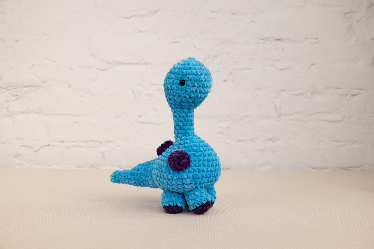 a crocheted toy of a blue dinosaur