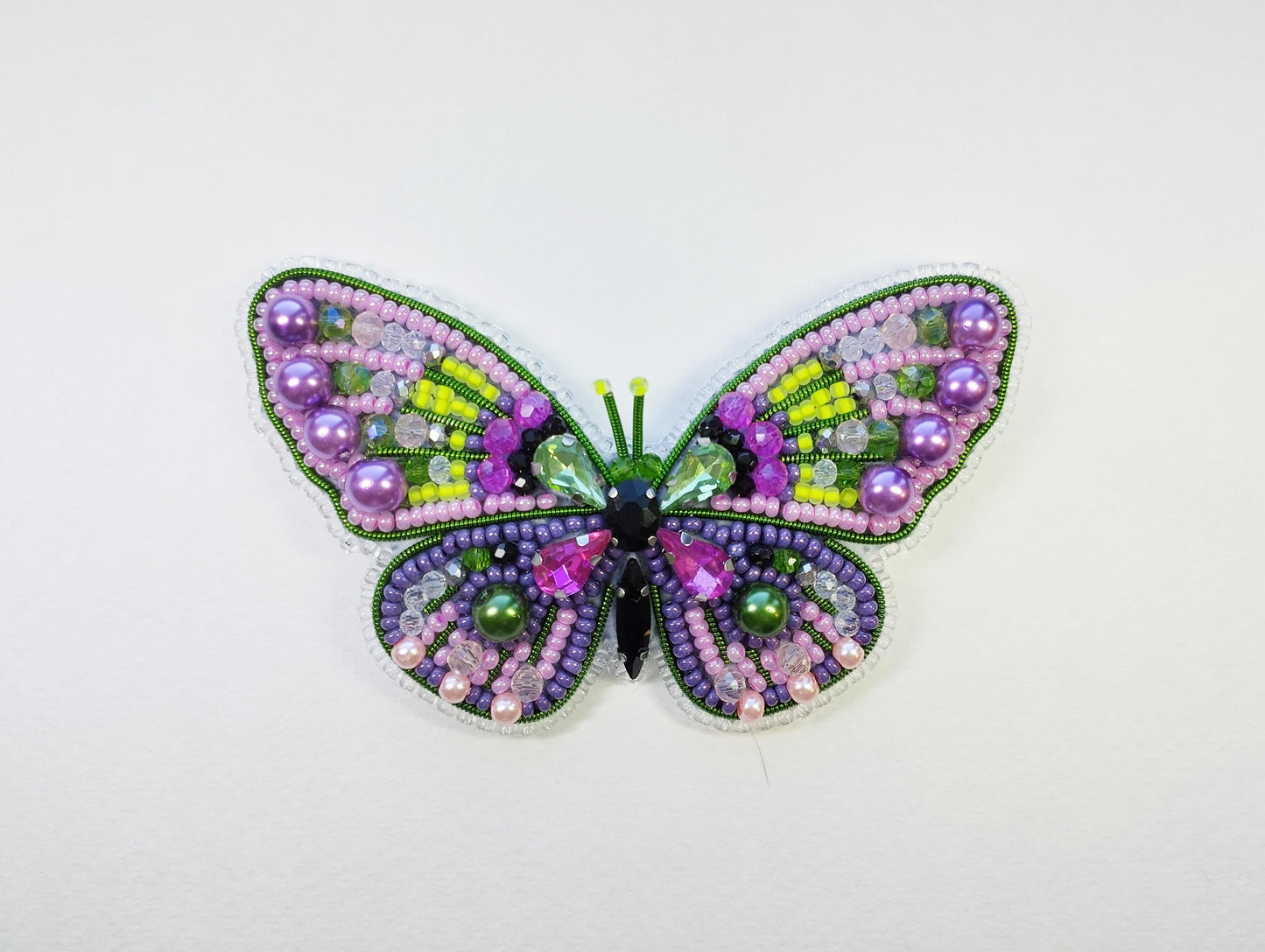 a colorful butterfly made out of beads on a white surface