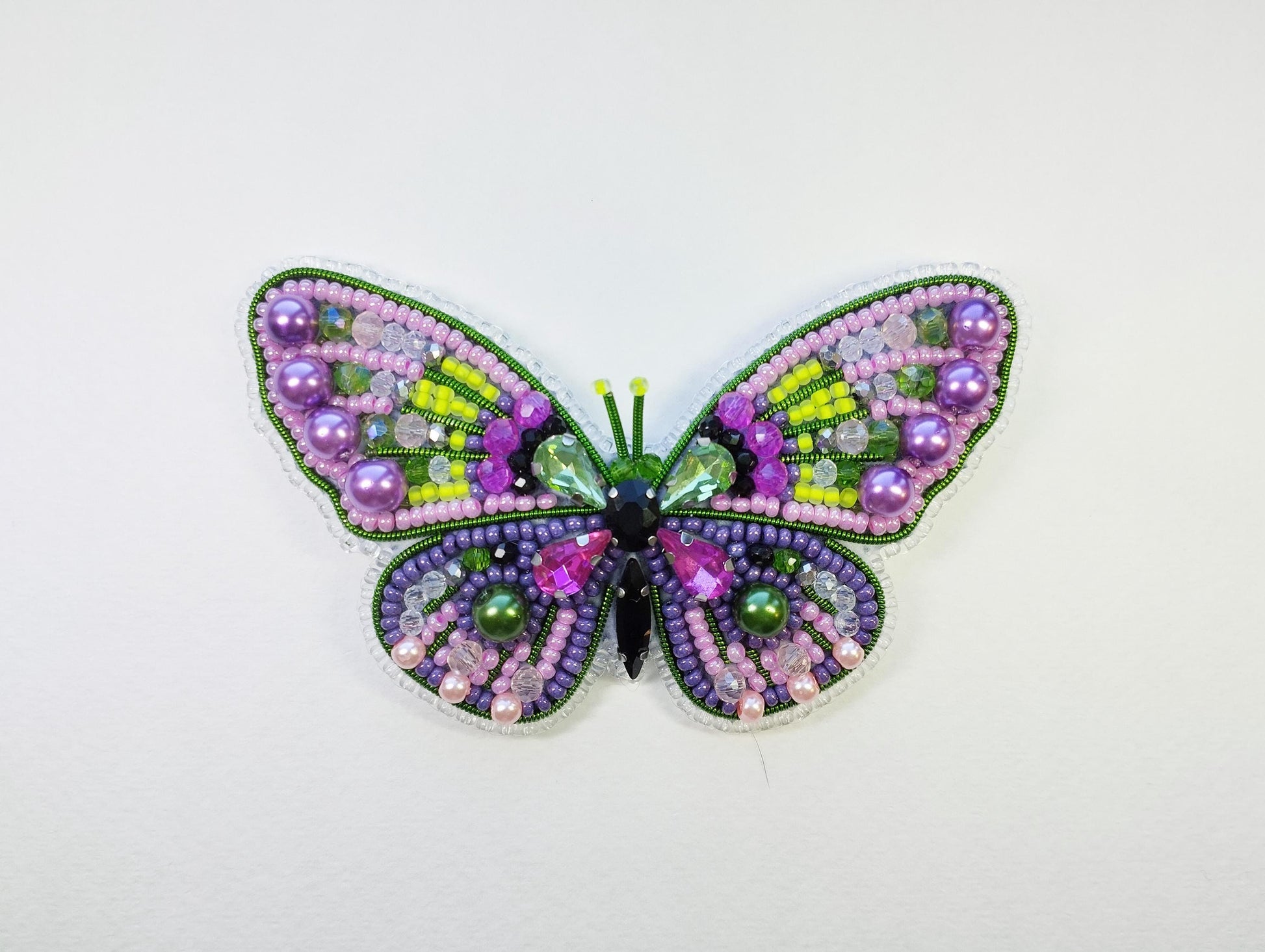 a colorful butterfly made out of beads on a white surface