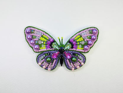 a colorful butterfly made out of beads on a white surface