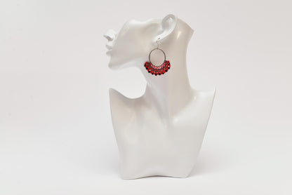 A white bust form is displayed against a plain white background, with a pair of red earrings hanging from the ear.