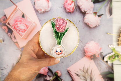 a person holding a small vase with a flower inside of it