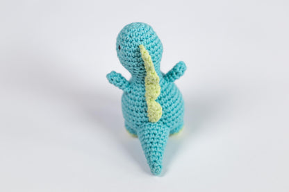 a crocheted toy of a blue dinosaur with a yellow tail