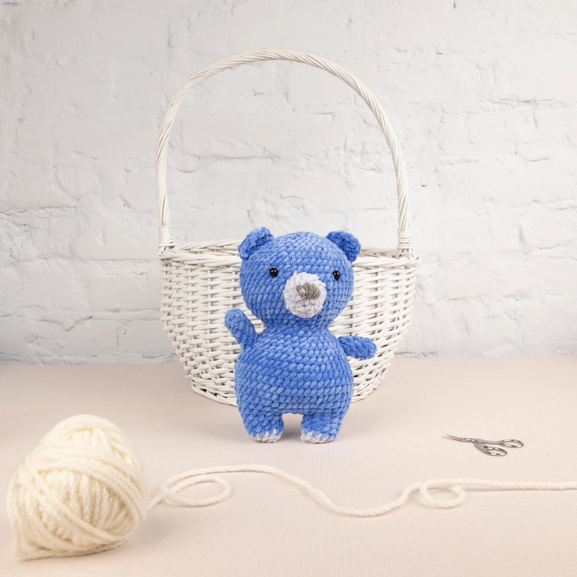 a blue teddy bear sitting next to a ball of yarn