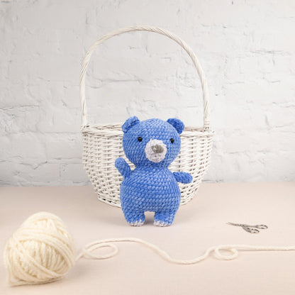 a blue teddy bear sitting next to a ball of yarn