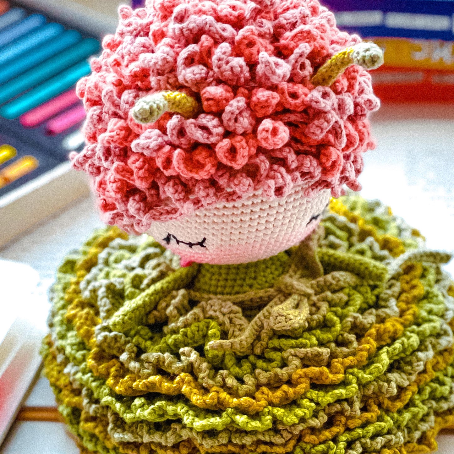 a crocheted doll sitting on top of a pile of yarn