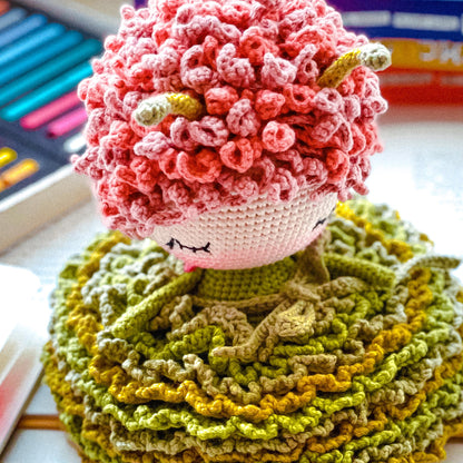 a crocheted doll sitting on top of a pile of yarn