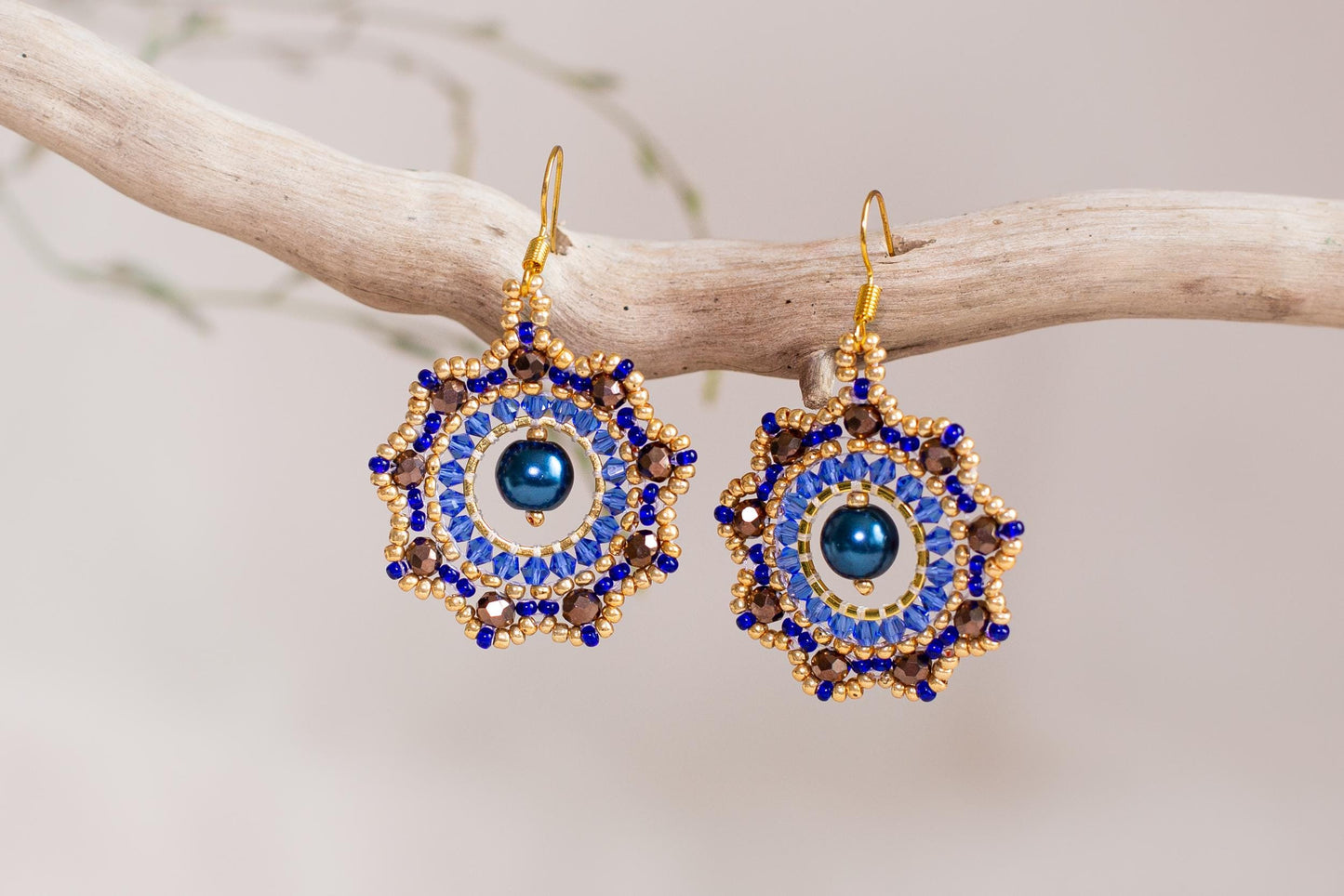 a pair of blue and gold earrings on a branch