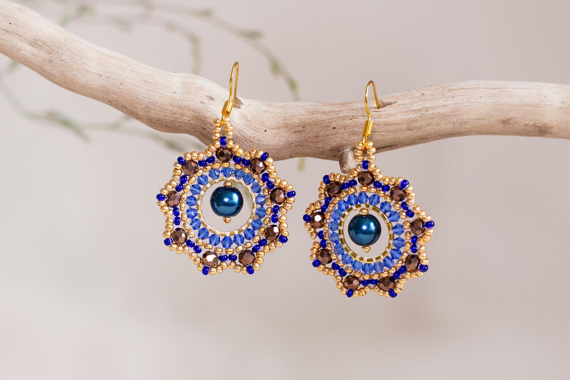 a pair of blue and gold earrings on a branch