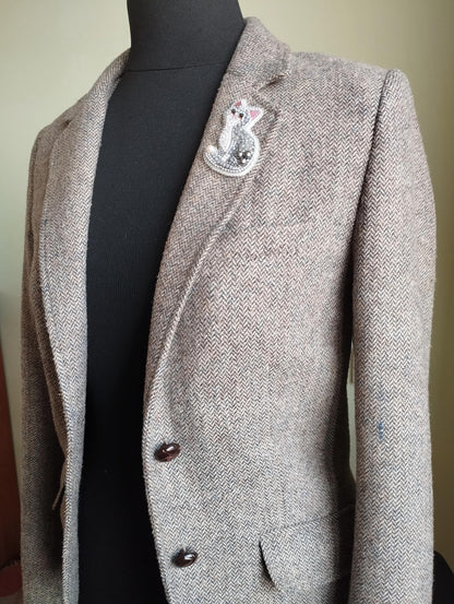 A gray tweed blazer with a decorative pin on the lapel.