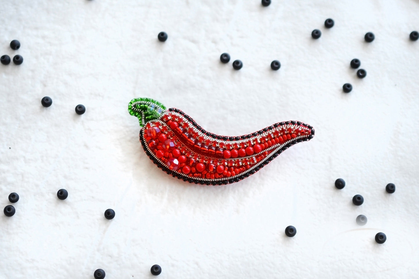 a red brooch with a green leaf on it