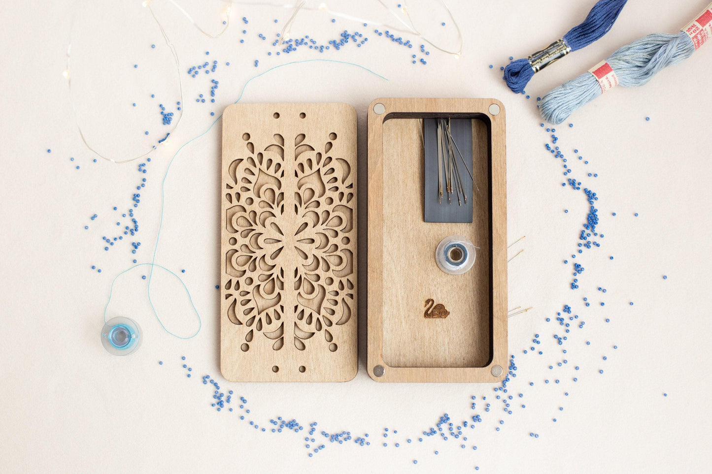 a wooden case with a laser cut design next to a spool of thread