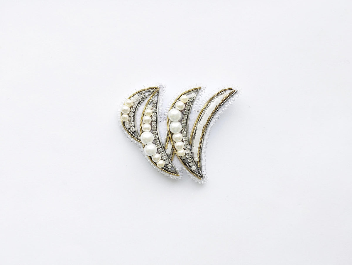 a pair of decorative earrings with a white and gold design, adorned with small pearls and beads.