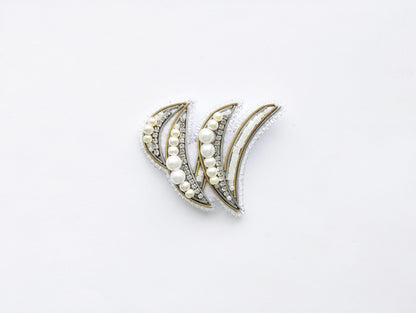 a pair of decorative earrings with a white and gold design, adorned with small pearls and beads.
