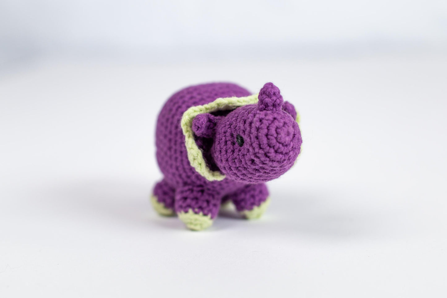 a small crocheted purple elephant toy on a white surface